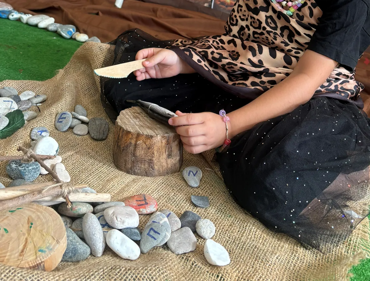 Boyalı taşlar, ahşap kütük ve kazı aletleriyle çalışan çocuk elleri